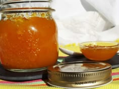 a jar filled with liquid sitting on top of a table next to a bowl and spoon