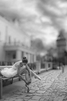 a woman sitting on top of a wooden bench next to a brick road with a quote written