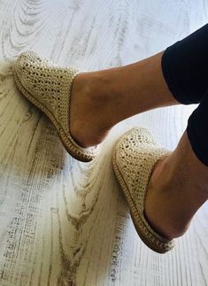 a woman's feet in crocheted slippers on top of a bed