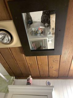 a bathroom with wood paneling and a mirror above the toilet