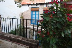 a wooden bench sitting in front of a building next to a flower filled bush with red flowers