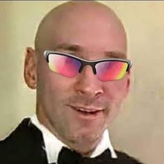 a bald man in a tuxedo with red and yellow mirrored sunglasses on his face