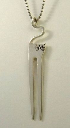 a silver necklace with two toothbrushes hanging from it's side on a white wall