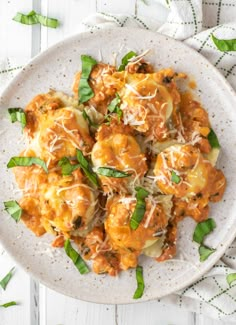 a white plate topped with pasta covered in sauce and cheese, on top of a green napkin