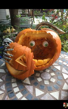 two carved pumpkins sitting on top of a table with eyes and hands in them