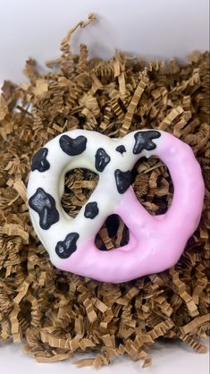 a pink and white donut with black spots on it's face is surrounded by wood shavings