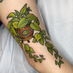 a woman's arm with a potted plant and leaves tattoo on the forearm