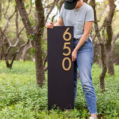 a woman standing next to a sign with the number 600 on it in front of some trees