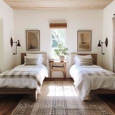 two beds in a bedroom with white walls and wood flooring next to each other