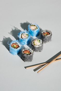 sushi rolls and chopsticks on a white surface with shadows coming from them