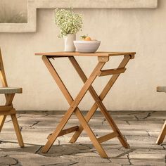 two wooden chairs and a table with a bowl of fruit on it