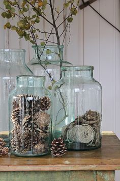 three glass jars filled with pine cones and twine