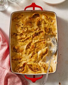 a casserole dish with meat and cheese in it on a red tray next to a pink towel