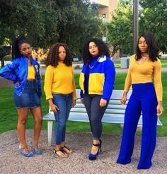 four women standing in front of a park bench