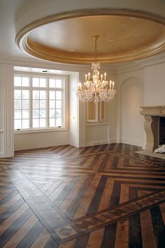 an empty room with a chandelier and wood flooring in the center is shown