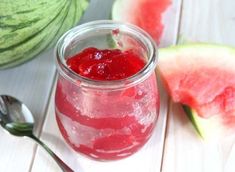 a glass jar filled with watermelon jam next to slices of watermelon