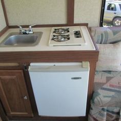 a small kitchenette with sink and stove in a trailer