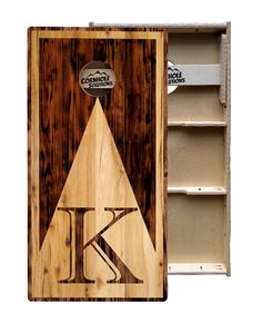 a wooden cutting board with the letter k on it next to an empty shelf for storage