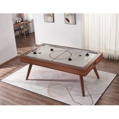 a table with a basketball game on it in front of a living room window and rug