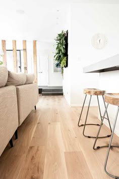 a living room filled with furniture and a wooden table next to a white wall on top of a hard wood floor