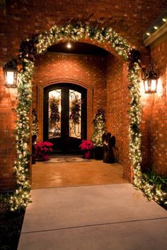 an entrance to a home decorated for christmas with lights and garland on the front door