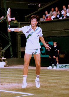 a man holding a tennis racquet on top of a tennis court in front of a crowd