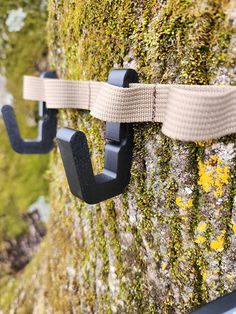 two black hooks are attached to a mossy wall