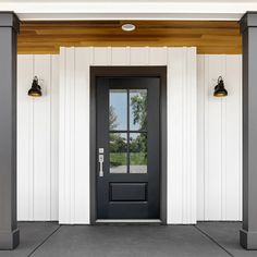 a black front door with two lamps on each side and white walls behind the doors