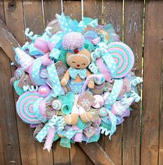 a wreath made to look like a teddy bear is hanging on a wooden fence with blue and pink decorations