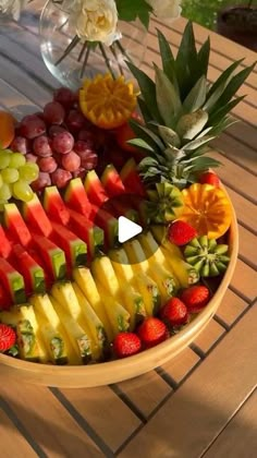 a bowl filled with lots of different types of fruit on top of a wooden table