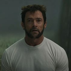 the wolverine man is looking at something in the distance with his face slightly obscured by an angry look on his face