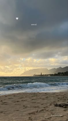 an image of the beach with waves coming in from the water and clouds above it