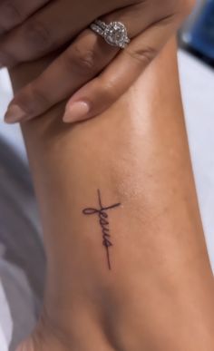 a woman's foot with a cross tattoo on it