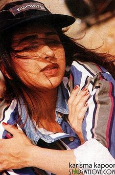 a woman with her hair blowing in the wind wearing a baseball cap and striped shirt