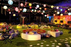 an outdoor event decorated with lights and paper lanterns hanging from the ceiling, surrounded by lawn furniture