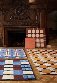 several different colored rugs on the floor in front of a fireplace