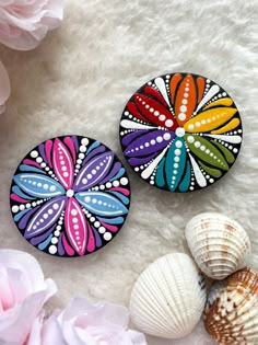 two colorful buttons sitting on top of a white fur covered floor next to pink flowers