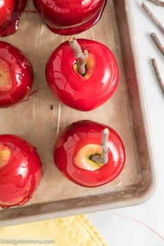 red apples sitting on top of a pan covered in melted chocolate