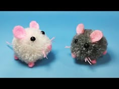 two small stuffed mice sitting next to each other on a blue surface with one mouse looking at the camera