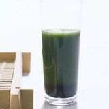 a glass filled with green liquid next to boxes