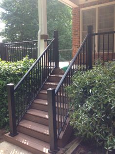 a set of stairs in front of a house with black railing and handrails