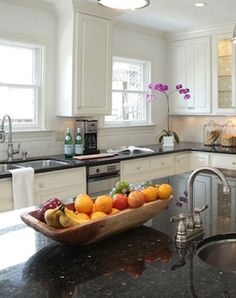 a bowl of fruit is sitting on the kitchen counter