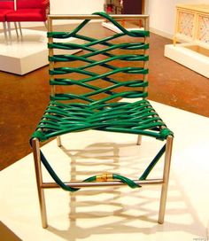 a green chair sitting on top of a white floor next to a red chair in the background