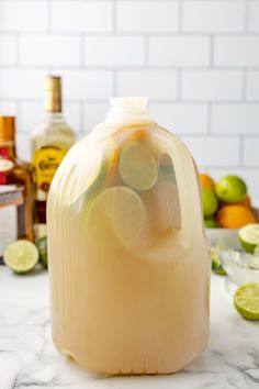 a pitcher filled with lemonade sitting on top of a counter next to limes