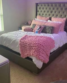 a bed with pink blankets and pillows in a bedroom