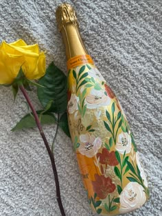 a yellow rose is next to a champagne bottle