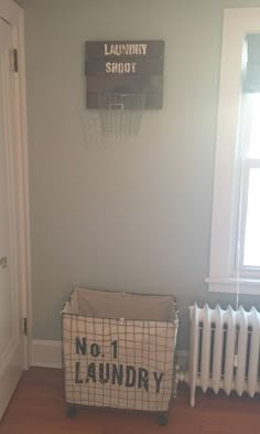 a laundry basket sitting in front of a radiator next to a sign on the wall