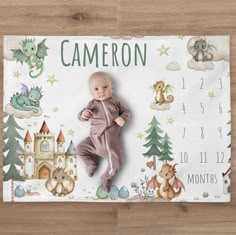 a baby laying on top of a wooden floor next to a calendar with dragon and castle images