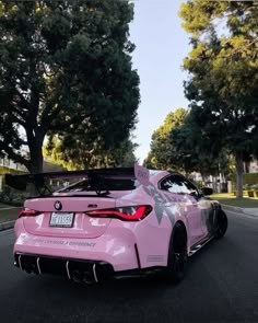 the pink sports car is parked on the street