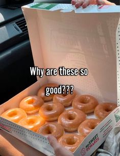 a box filled with donuts sitting on top of a car seat next to a persons hand